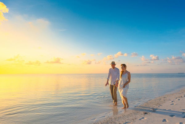 Couple marchant au bord de l’eau au coucher du soleil