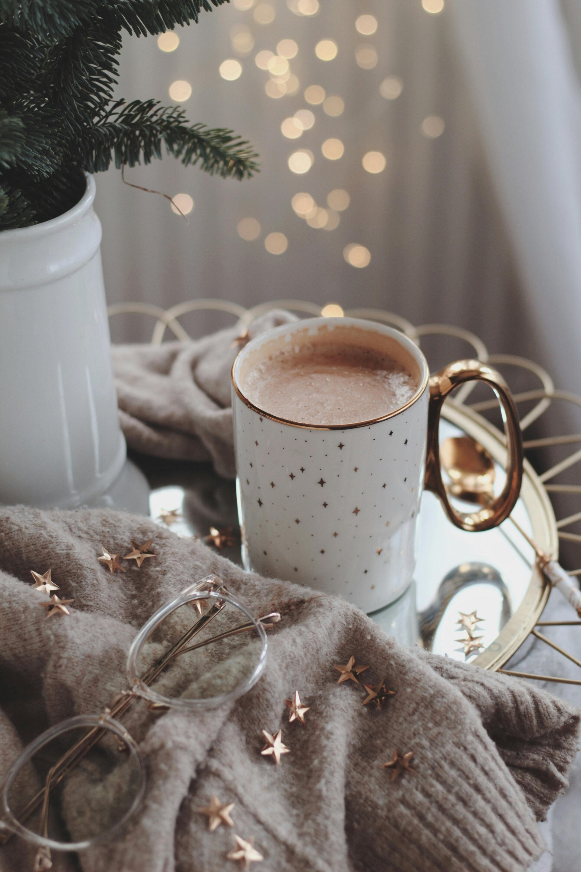 A warm mug resting on a soft blanket with twinkle lights in the background, capturing a quiet morning ritual and a moment of calm.