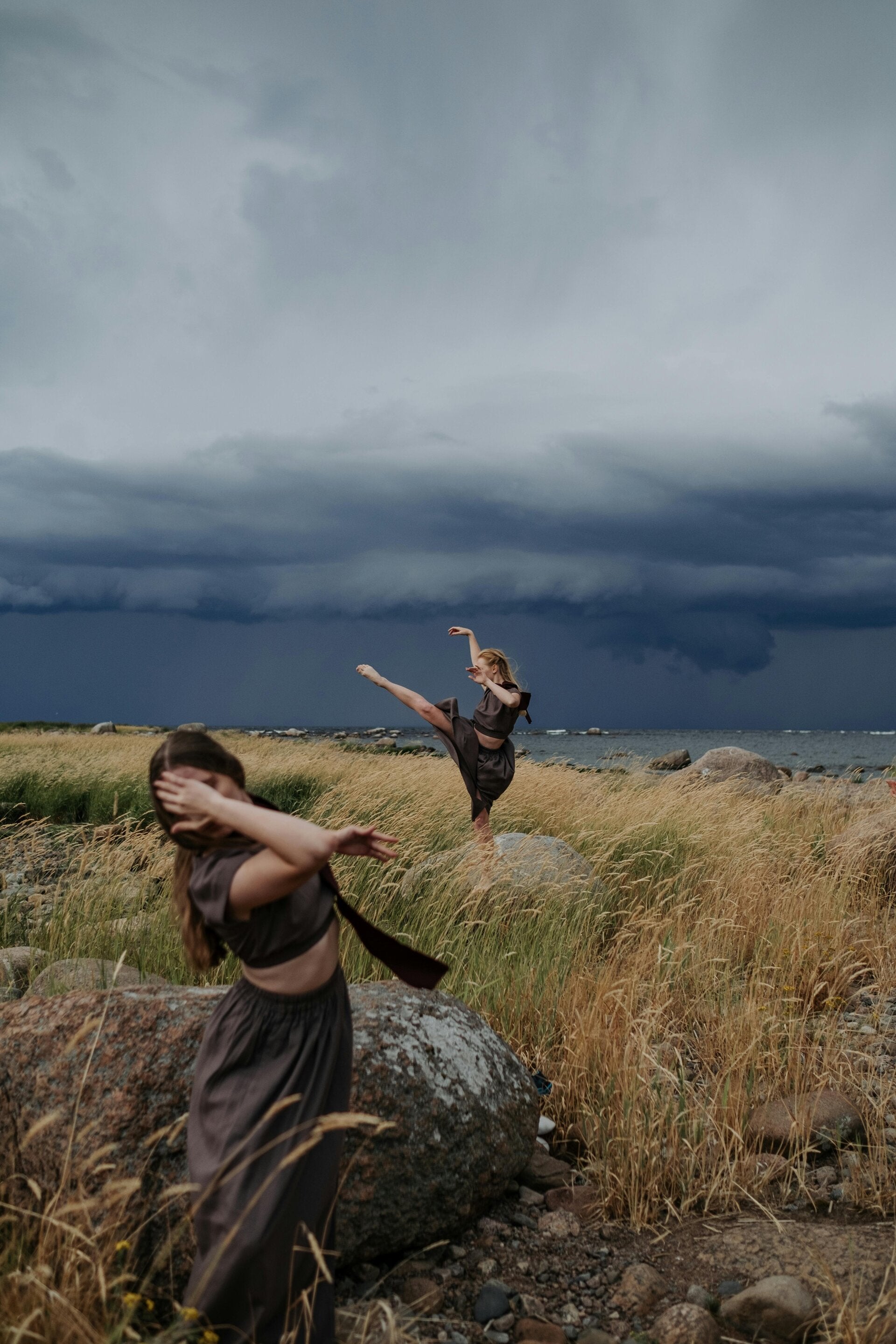 Donne danzano in campo, cielo tempestoso. Gestione emozioni, equilibrio interiore.