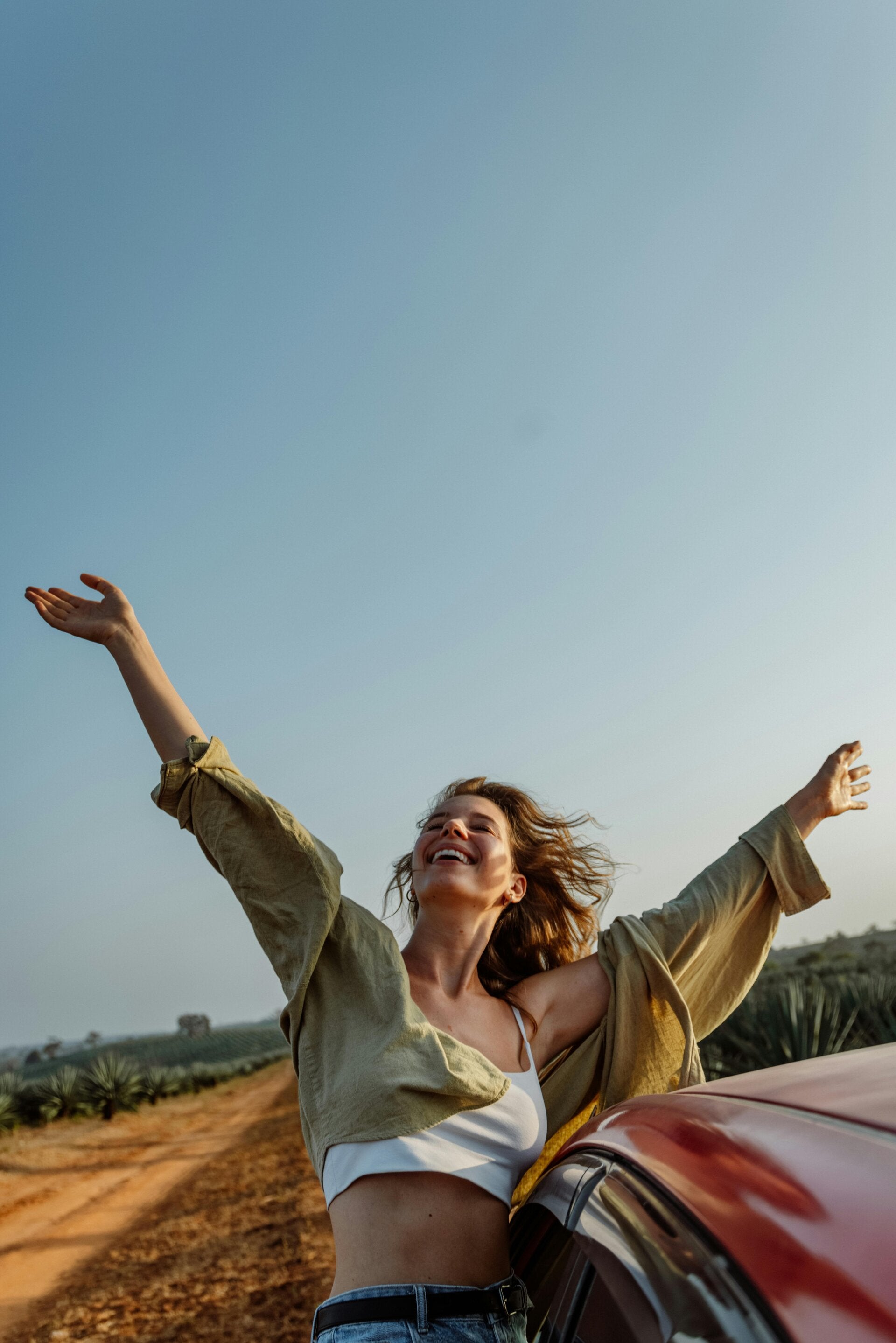 woman hanging out car window free in the wind smiling