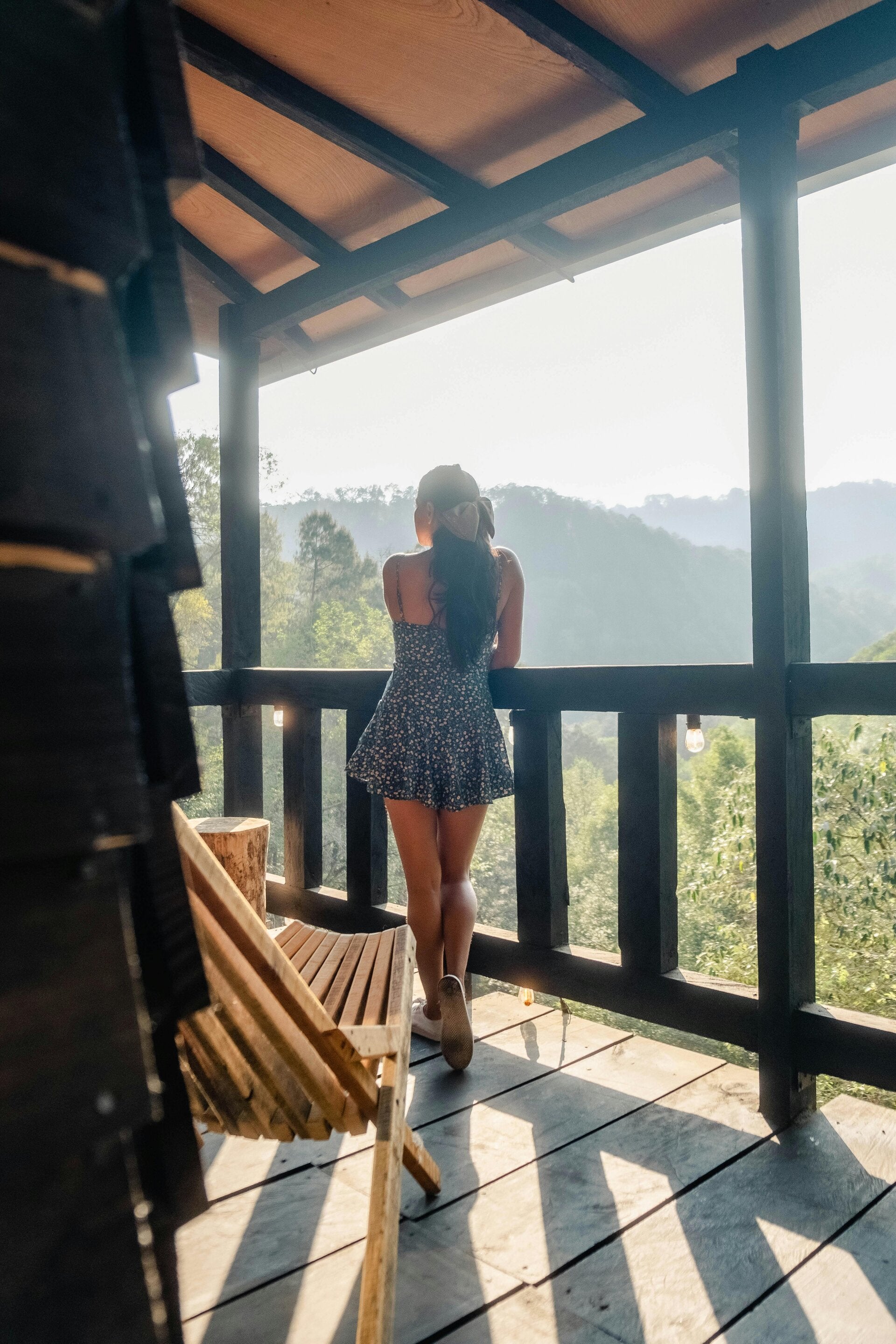 femme de dos sur une terasse en bois qui regarde un paysage