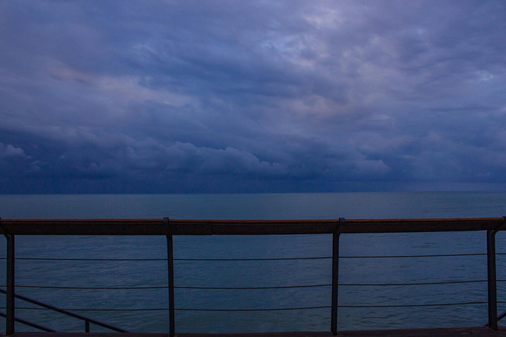 Sunset beside an outdoor ship deck with railings and evening lights