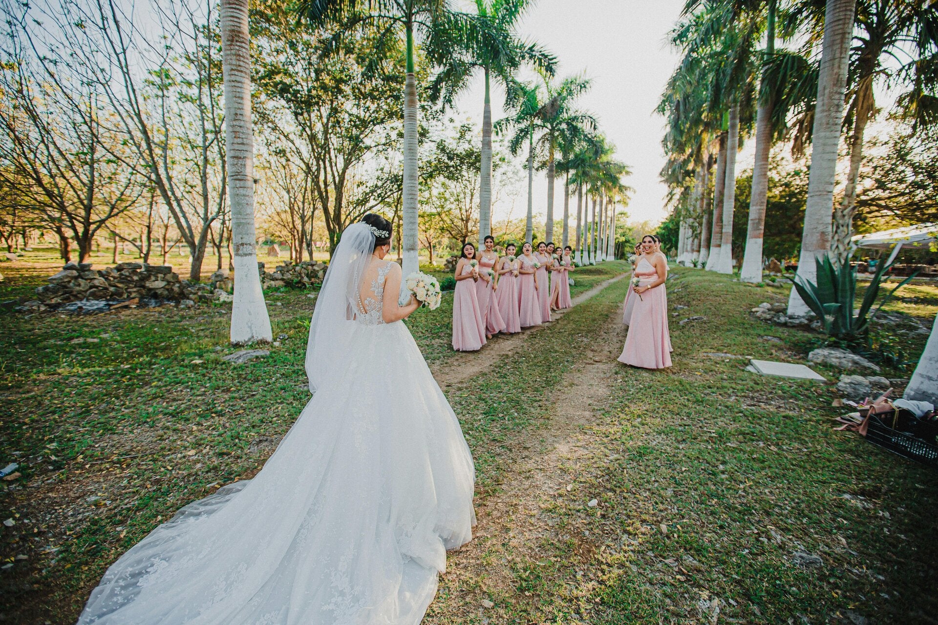A bride greeting her bridesmaids as she walks down the palm tree lined aisle. We can help your arrange your large party weddings events.