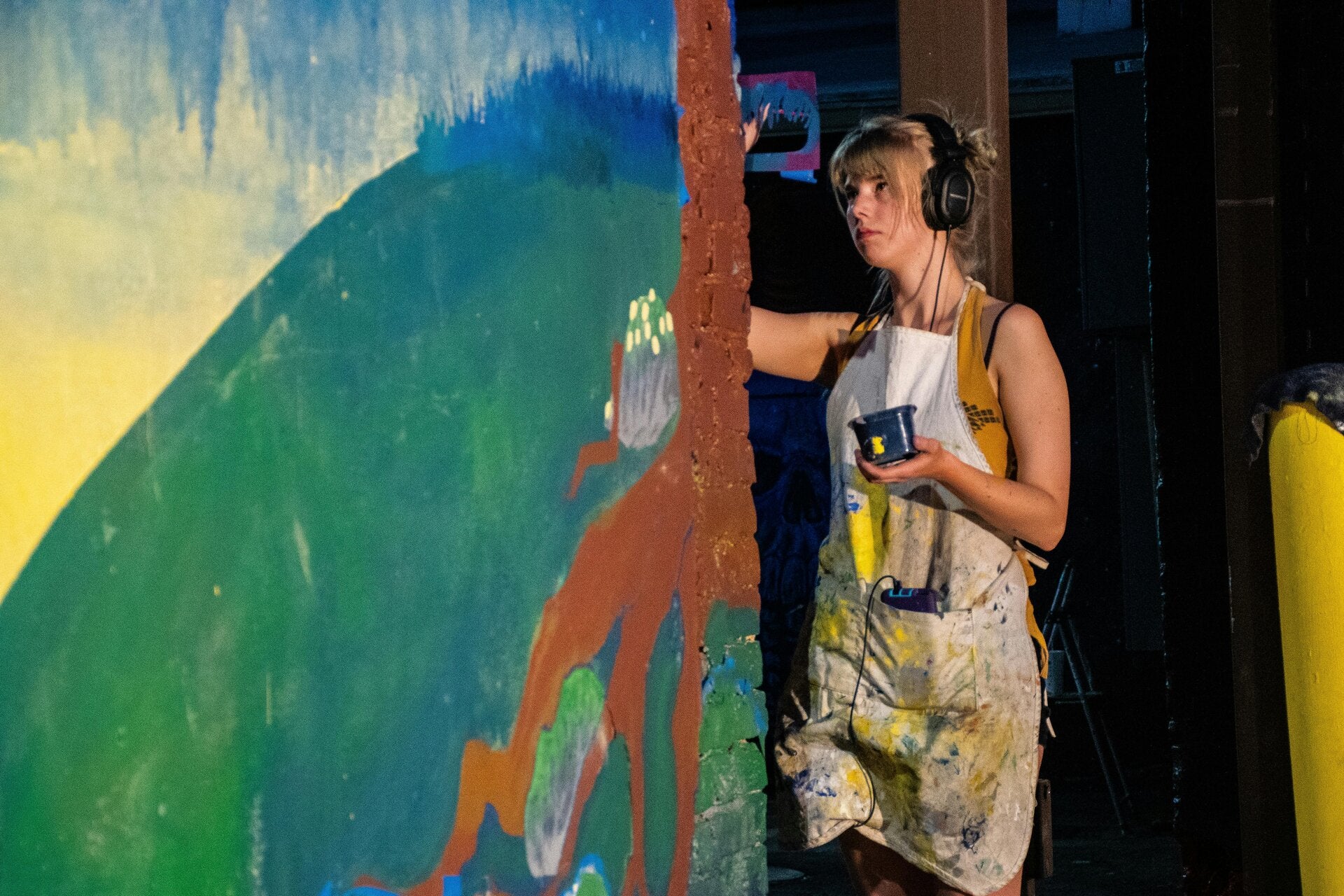a bust of a woman wearing headphones. she is infront of a beehive and has a crown of swarming bees.