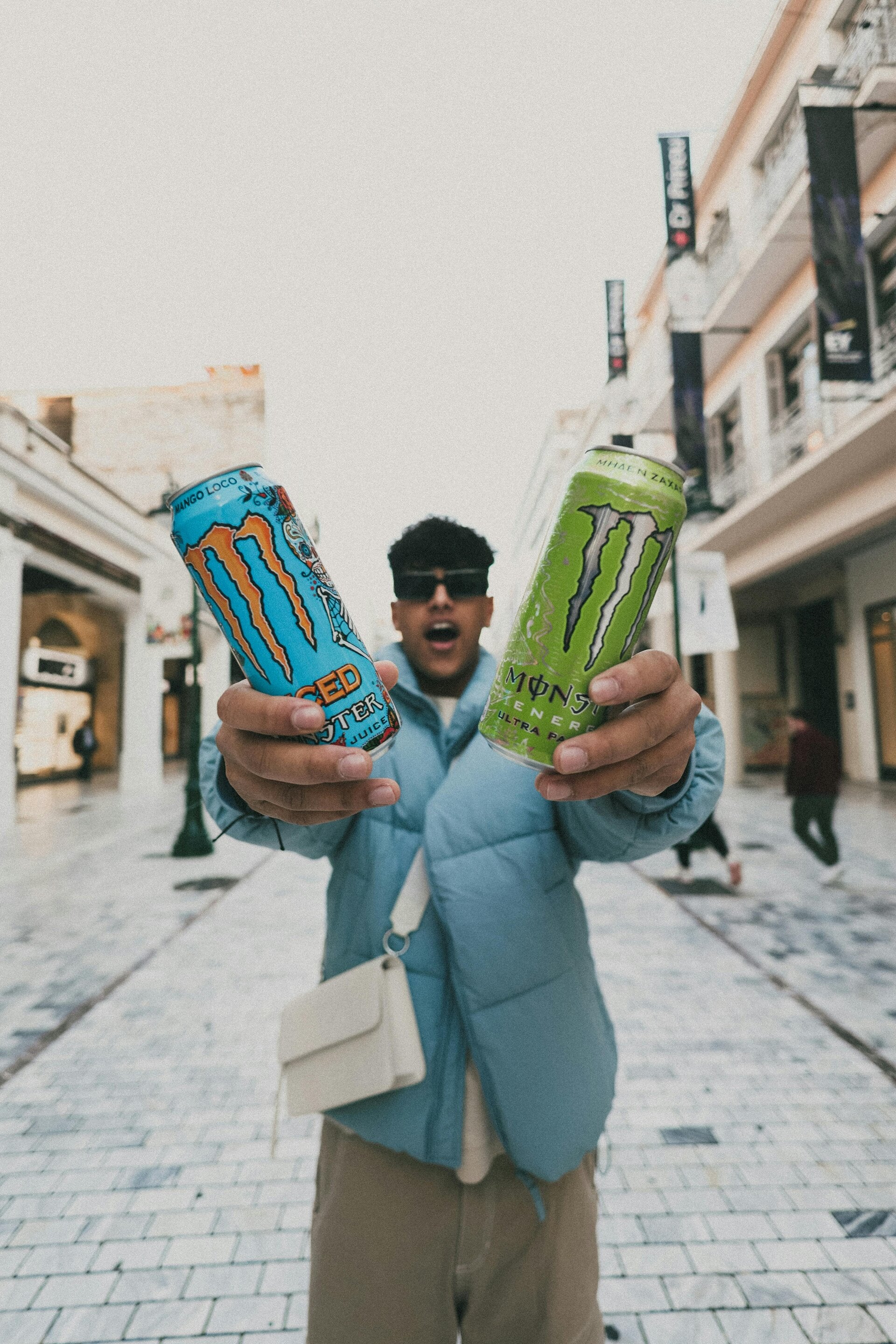 une homme tenant dans chaque main 2 canettes de monster
