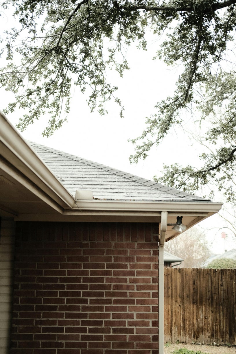 Roof with storm damage showing shingles lifted by wind