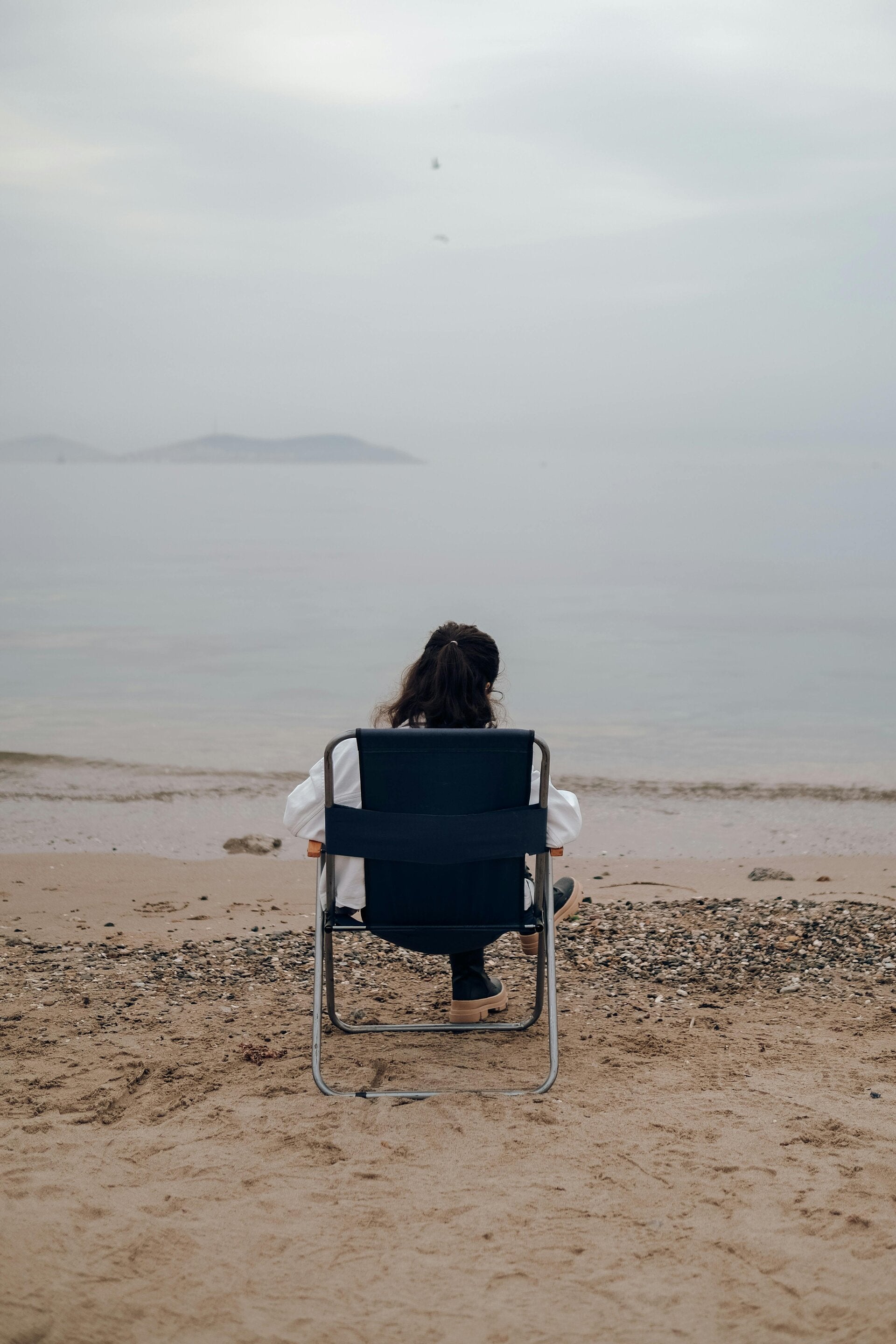 Persona disfrutando del silencio y la calma frente al mar, reflexionando sobre la vida