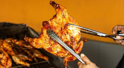 Chef is holdig a grilled butterflied chiken