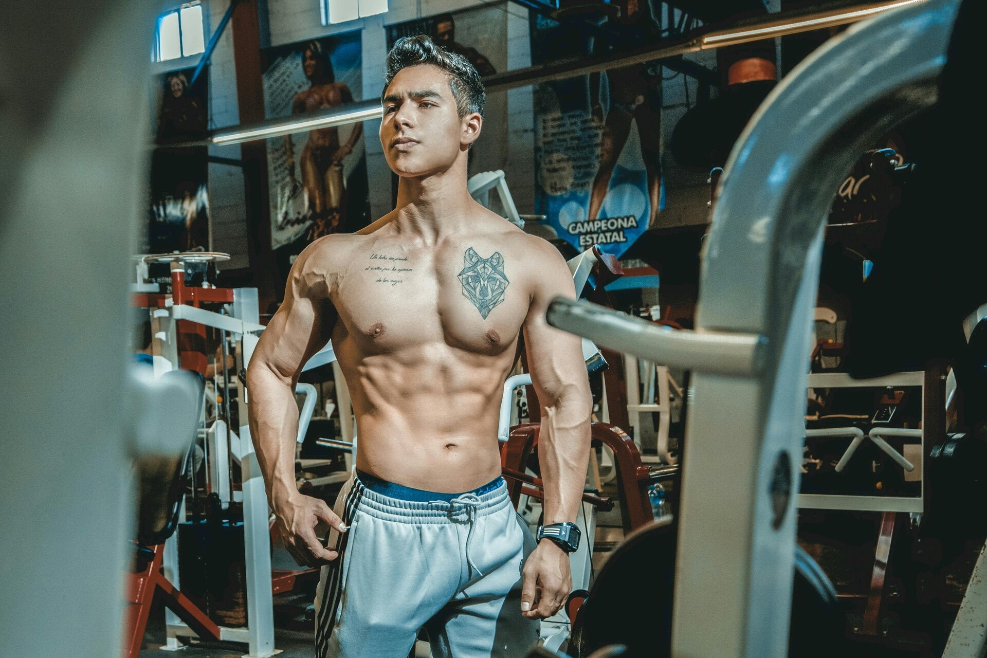 un homme torse nu et musclé se tenant debout dans une salle de sport