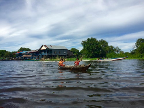 Enfants ramant sur une rivière bordée de végétation