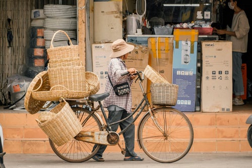 Vendeuse poussant un vélo chargé de paniers