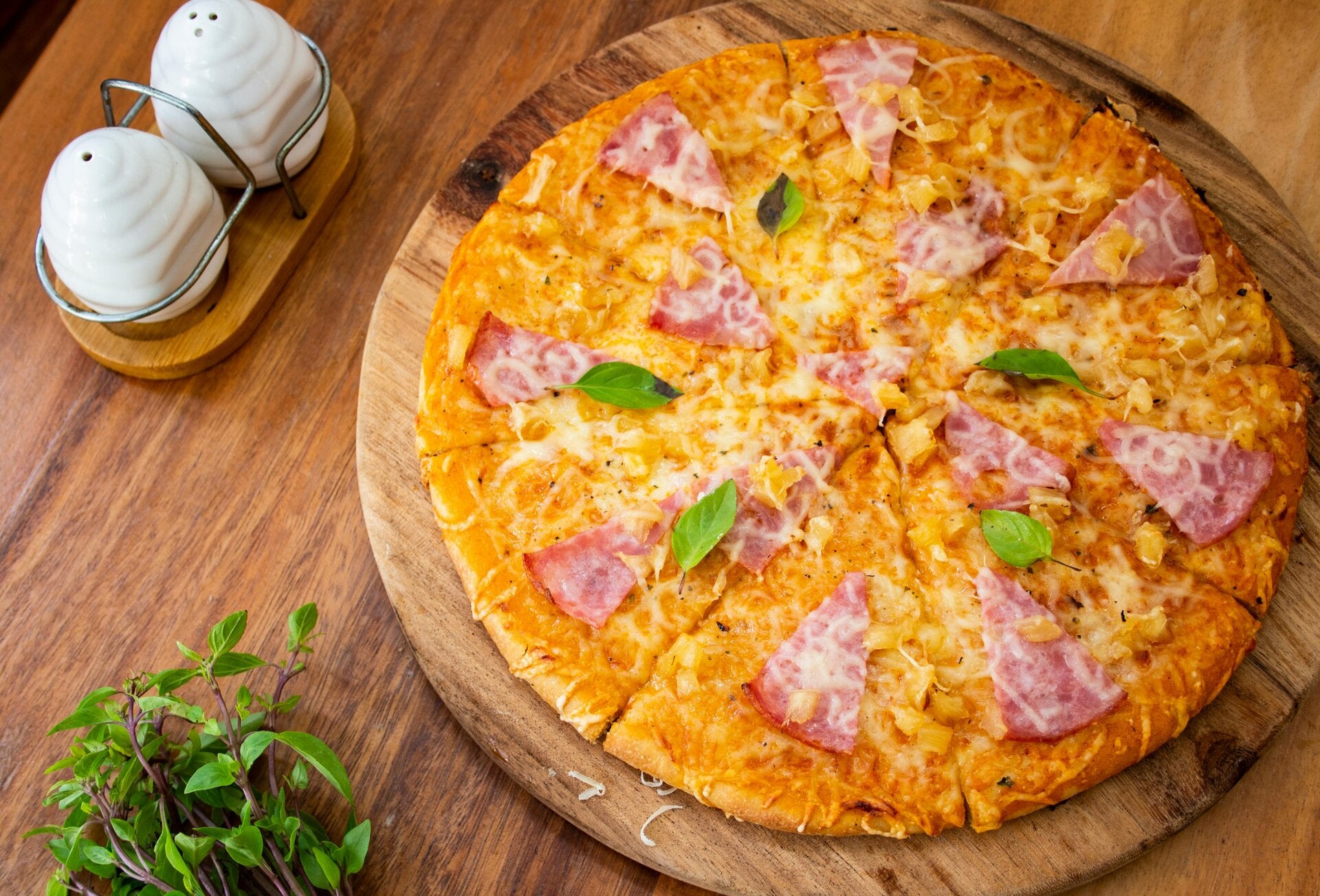 A fresh Cannabis Pineapple Ham Pizza with a creamy white sauce base, mozzarella cheese, and golden pineapple chunks, ideal for cannabis edibles