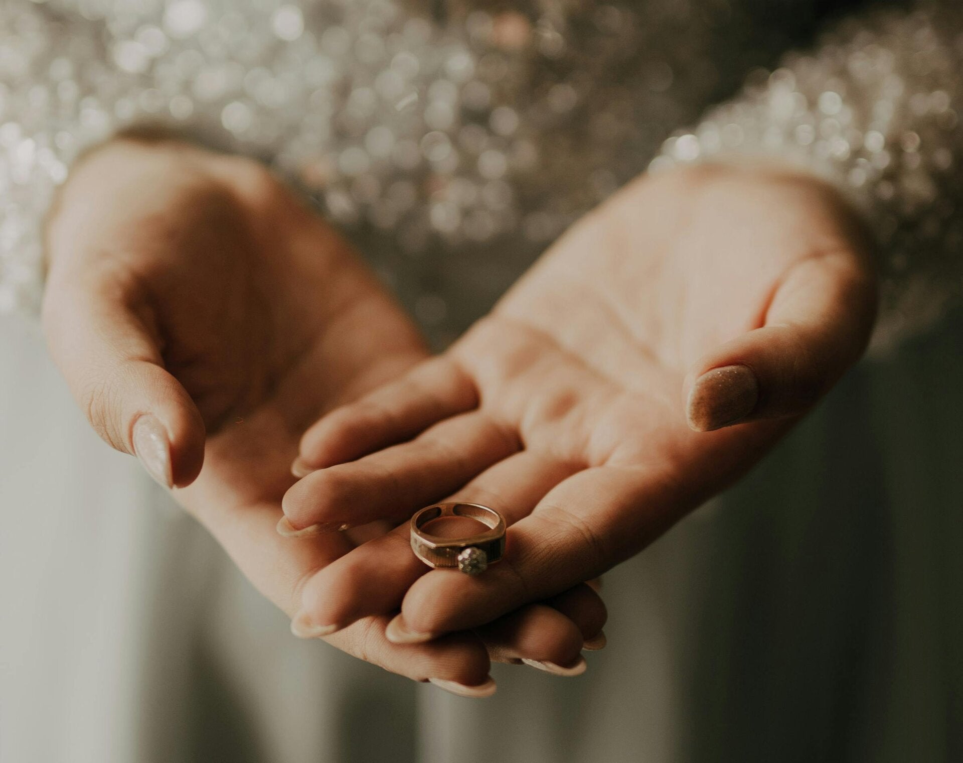 Handen van een vrouw die een gouden trouwring vasthoudt