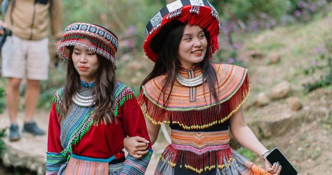 Two women dressed in vibrant traditional attire in an Asian setting, standing gracefully and reflecting the rich cultural heritage of their surroundings
