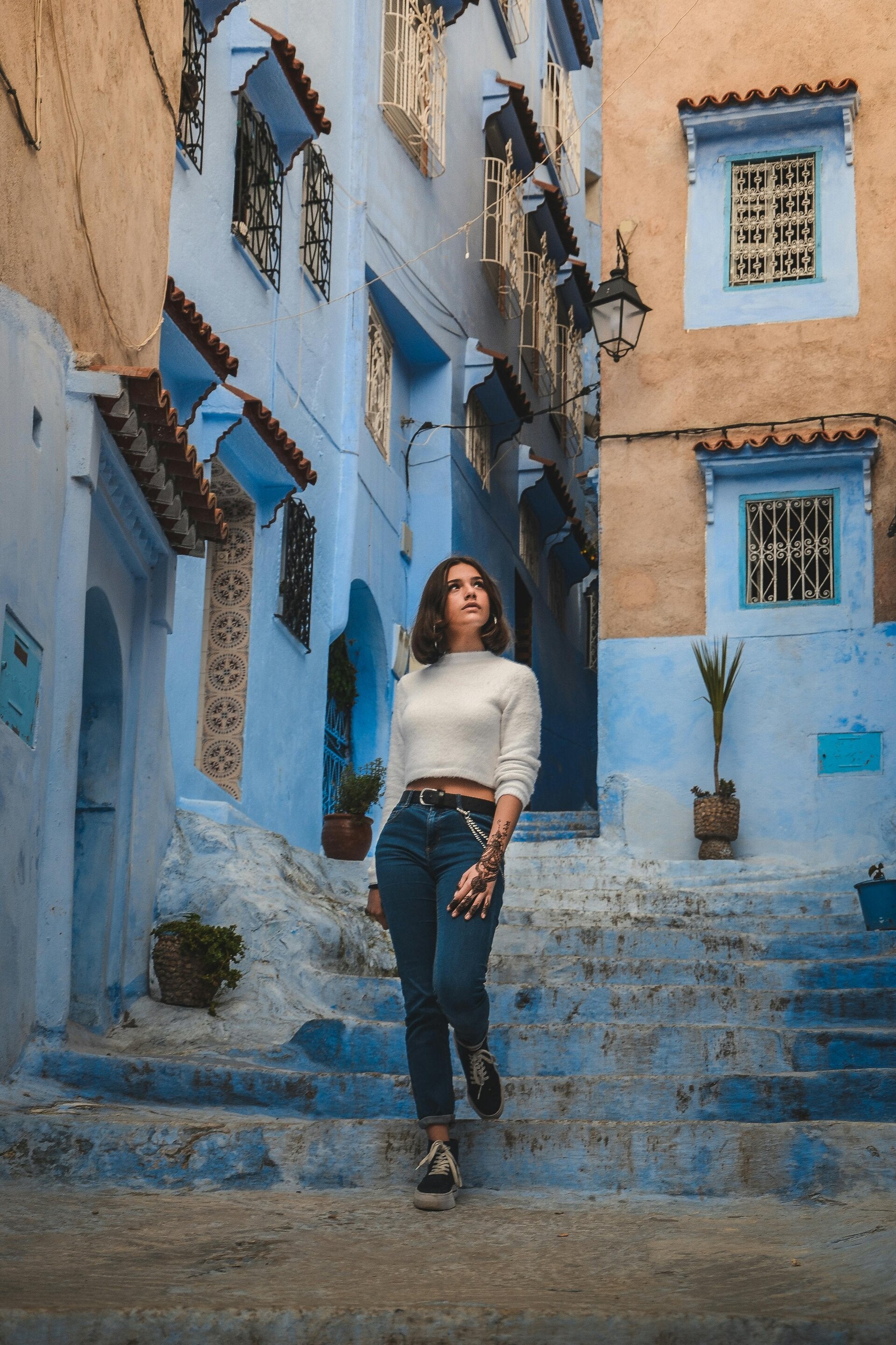 “Yoga retreat participant gazing at a boat in Northern Morocco with the iconic blue city of Chefchaouen in the background”