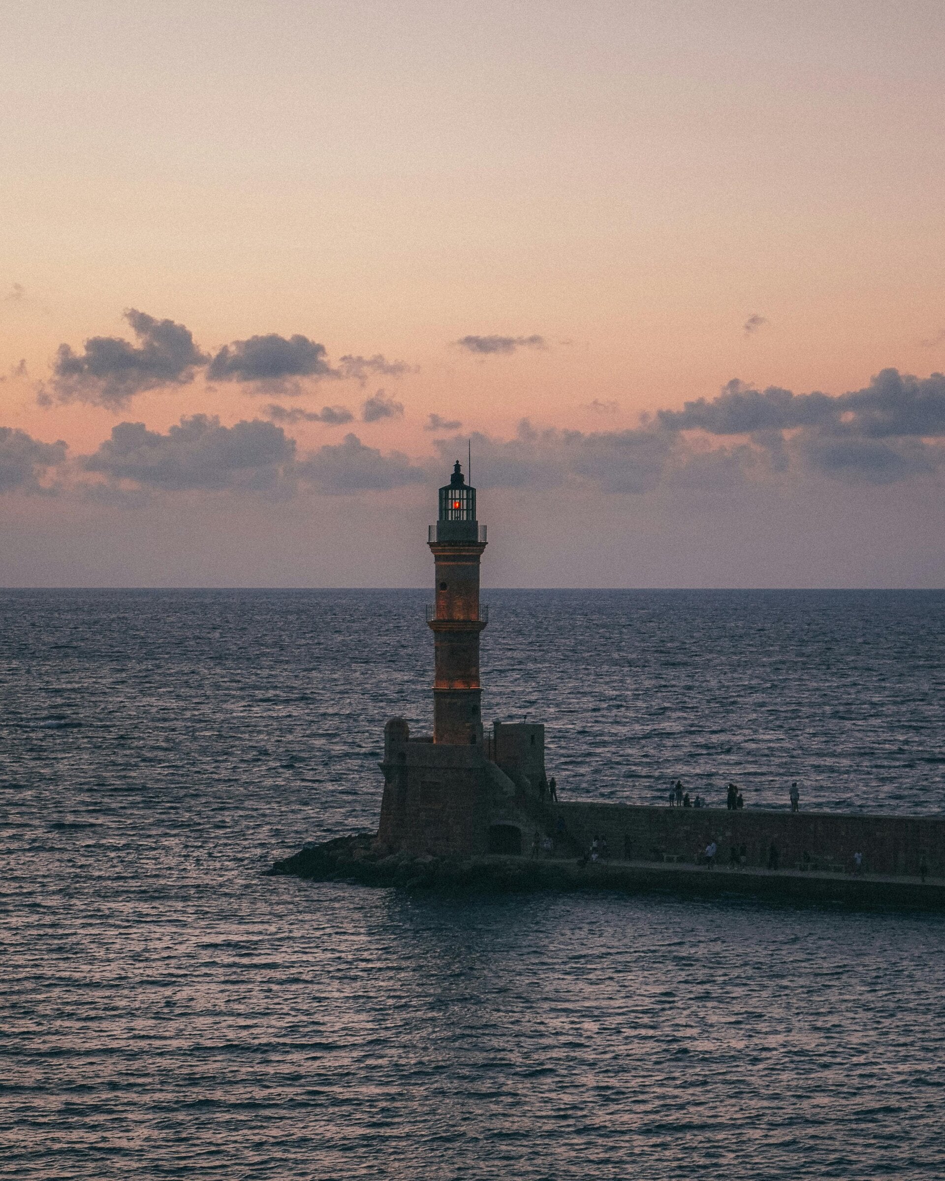 Een vuurtoren omringt met een rustige zee tijdens zonsopgang