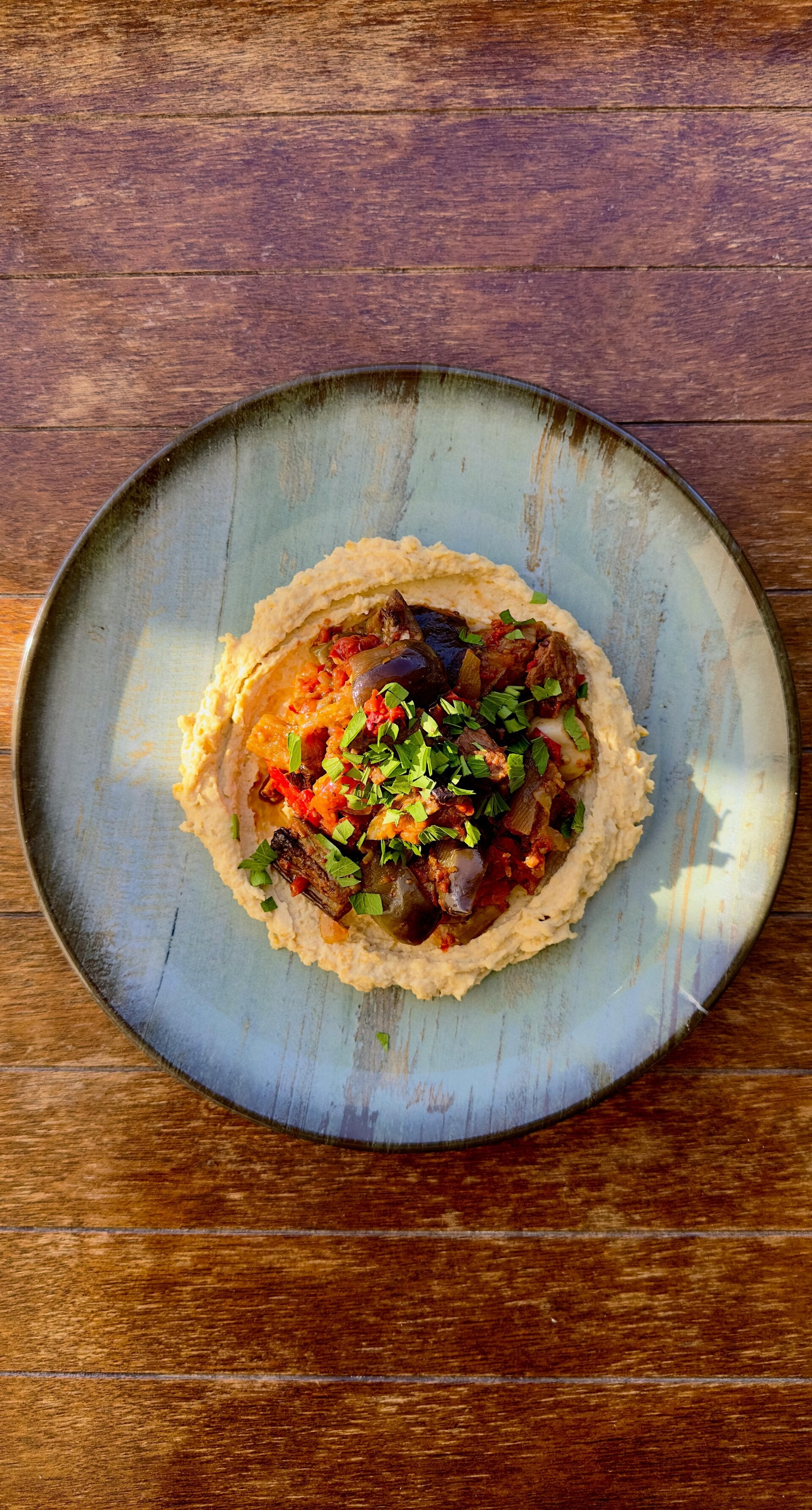 A plate of houmous with aubergines and chutney