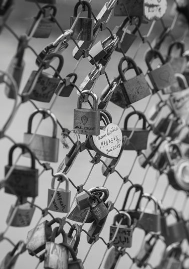 Black and white photo of numerous padlocks on a fence symbolizing locking in life insurance rates early for long-term protection.