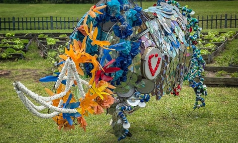 A creatively assembled cow sculpture, crafted entirely from recycled materials. Bits of metal, plastic, and repurposed objects come together to form an eco-friendly masterpiece, showcasing sustainability and artistic ingenuity