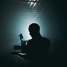 Shadowy picture of a man with lights and a camera