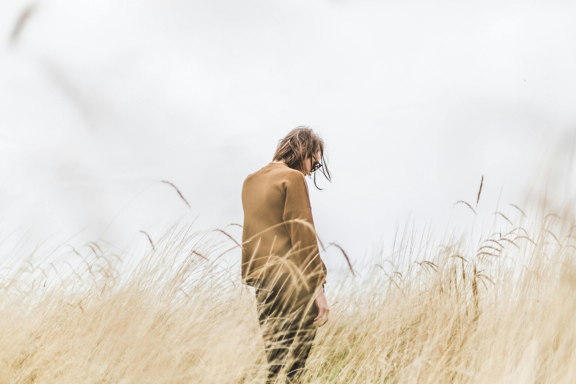 Vrouw met gebogen hoofd staand in de natuur met emoties rondom verdriet en verlies