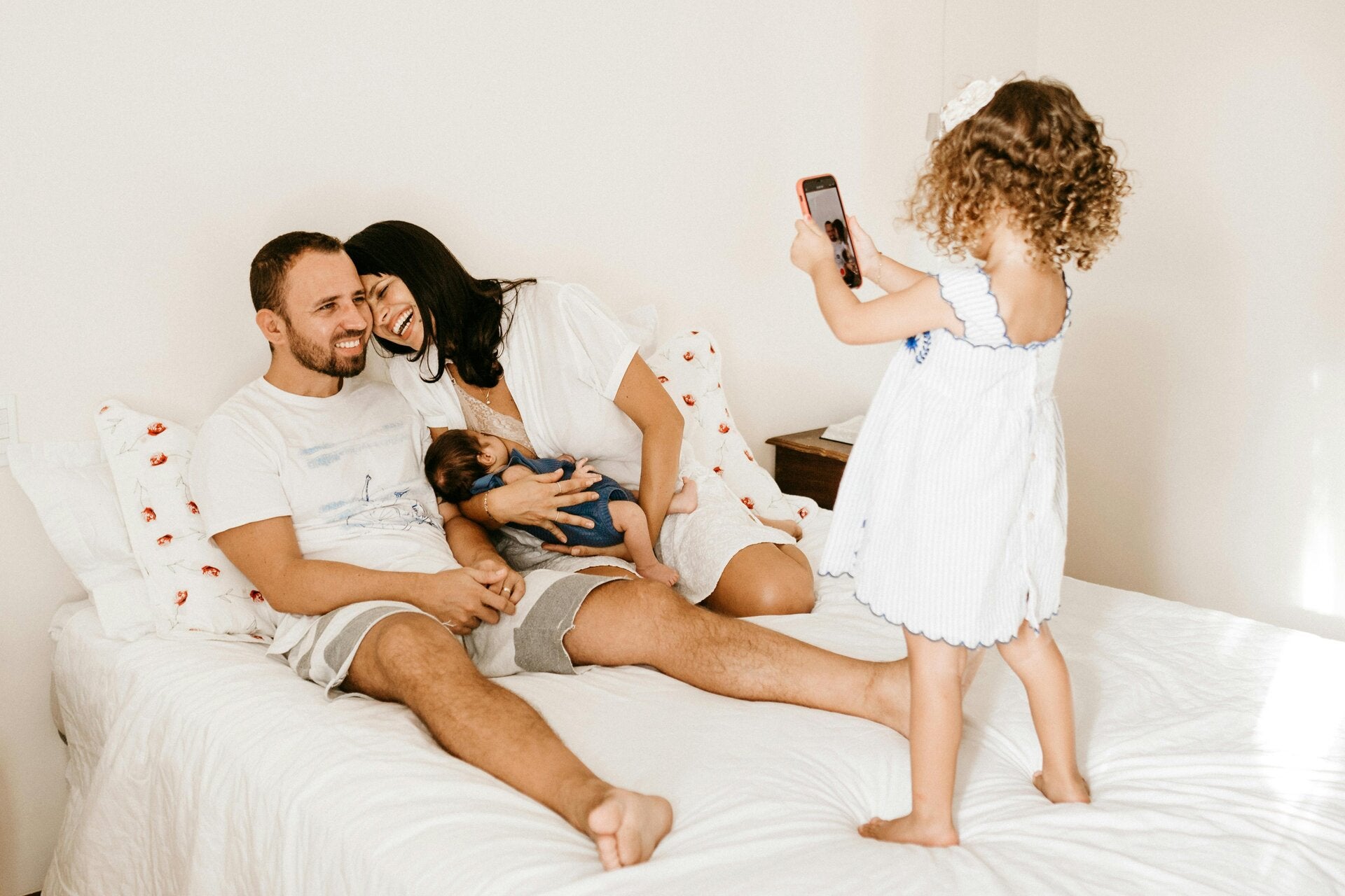 Famiglia felice con due bambini su un letto, la figlia scatta foto. Genitore, famiglia moderna, era digitale.