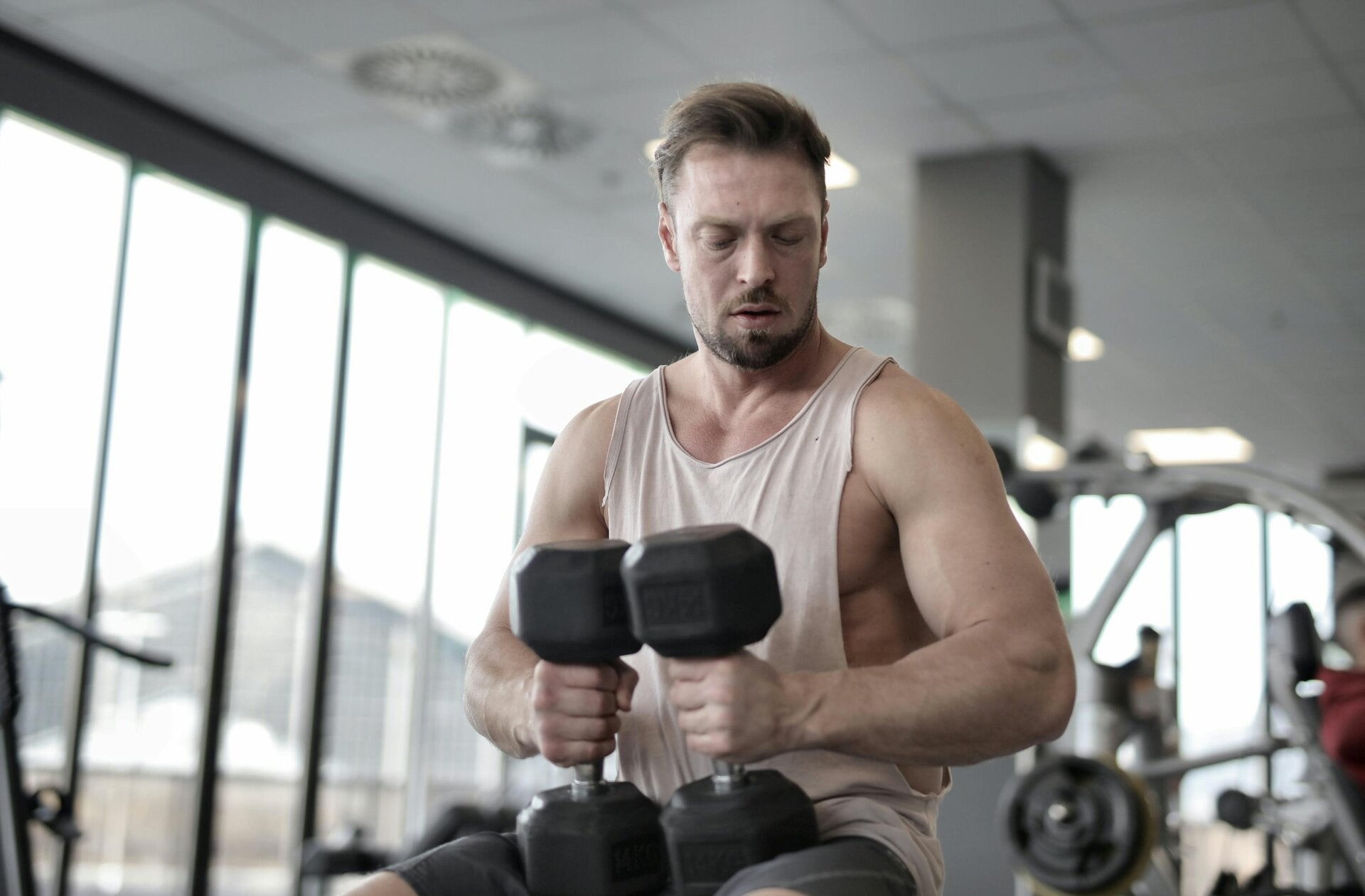 Muskelpflege: Mann in Fitnessstudio mit Hanteln