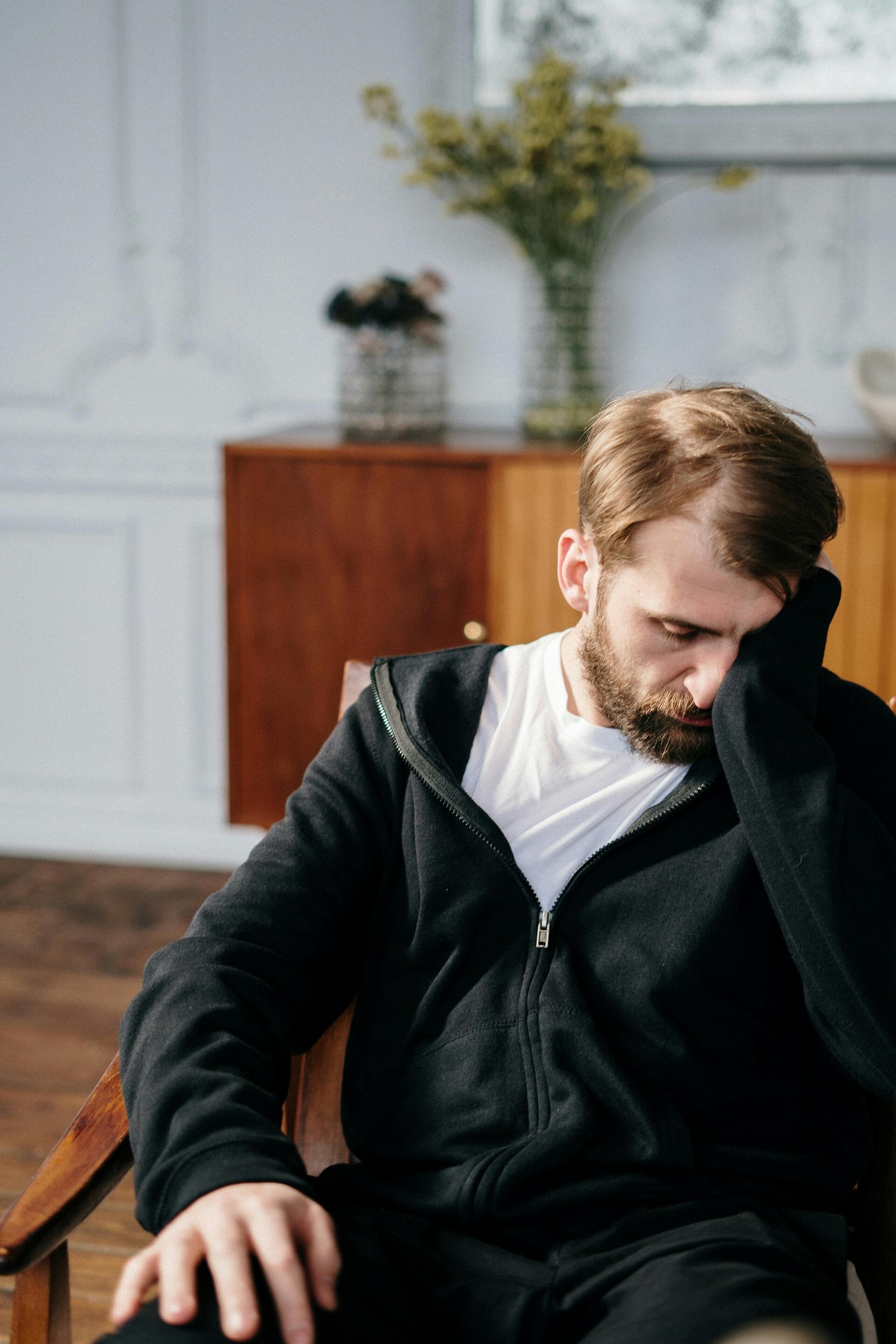 Man with a beard with his face rested on his hand.