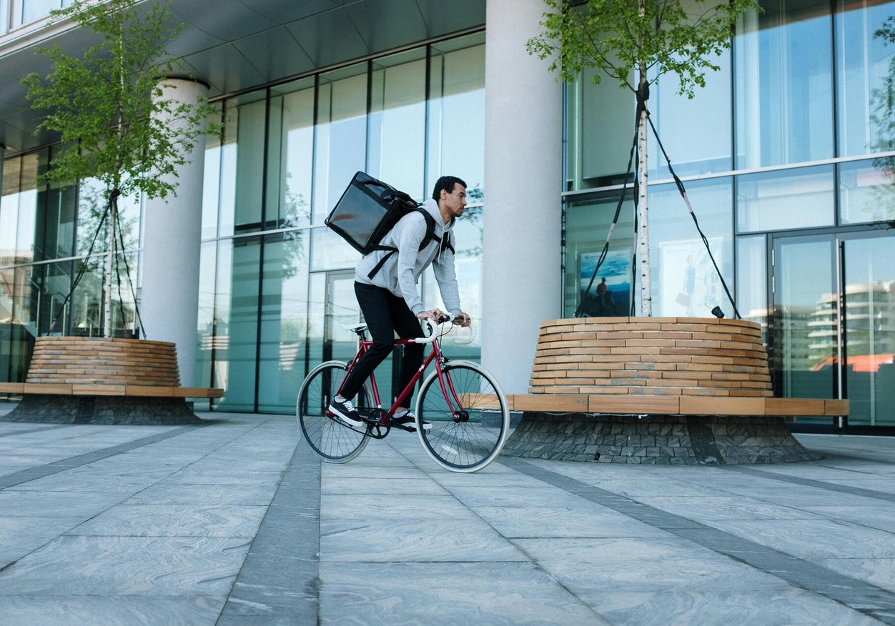 Courier riding a bicycle through a city plaza