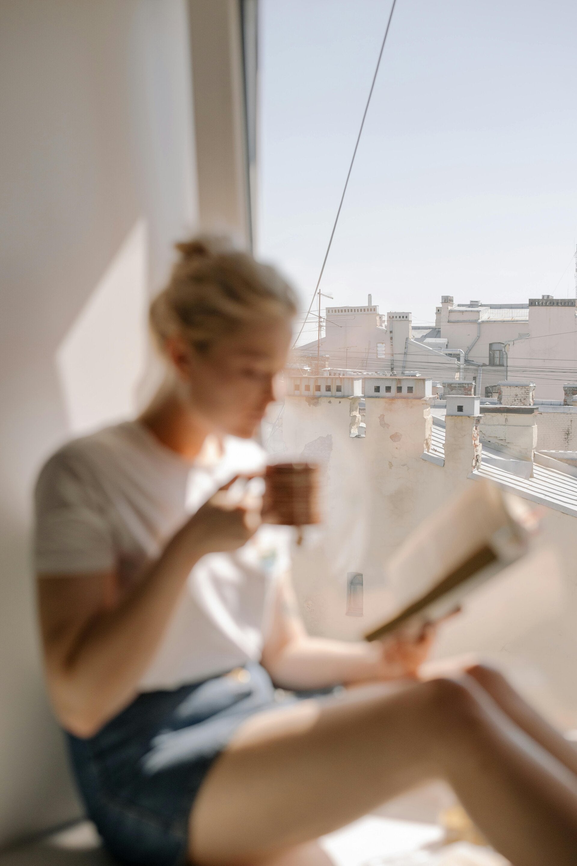 A woman writes in a journal by the window, quietly reflecting on the impact she wants to leave behind.