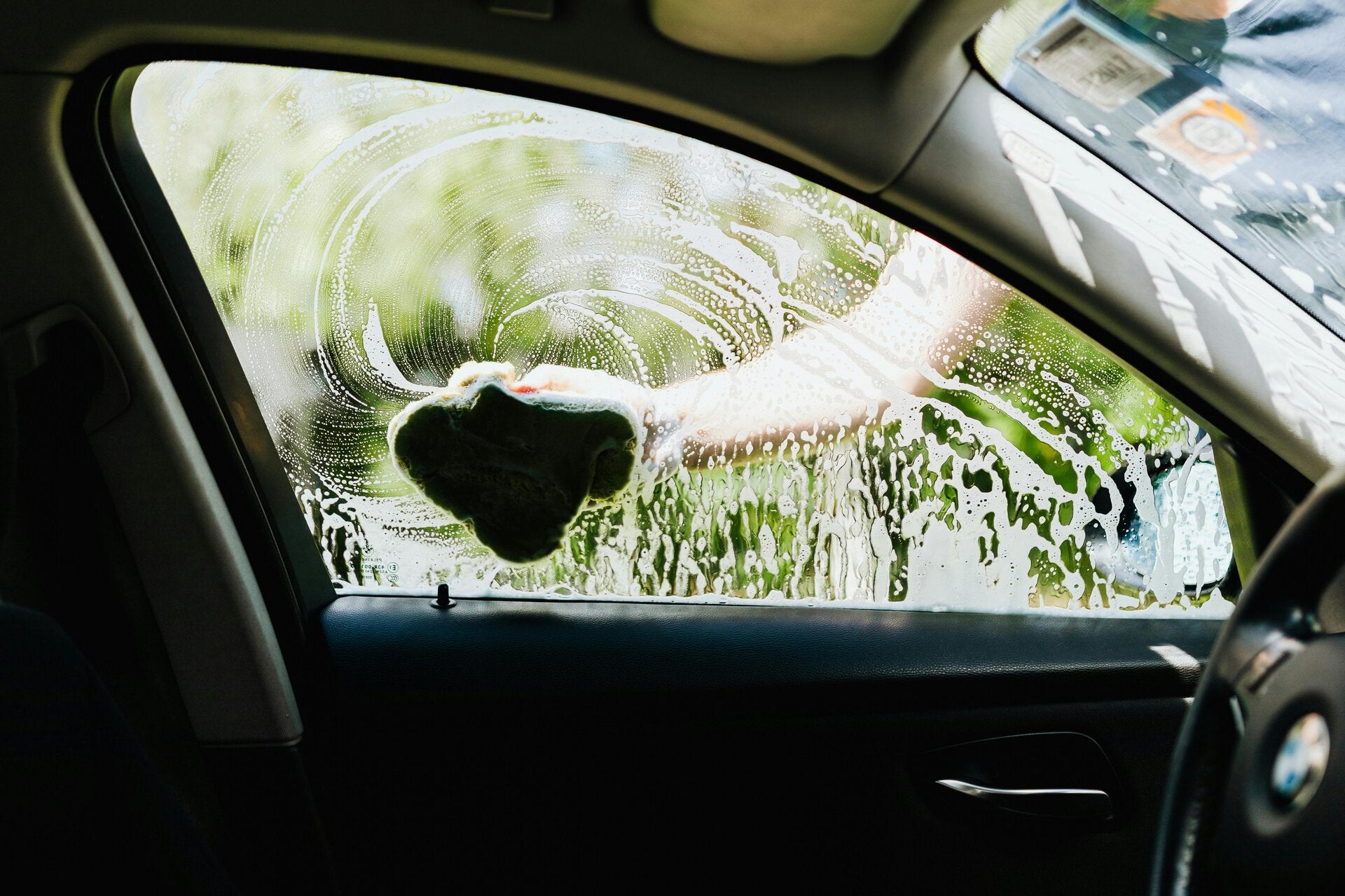 a close up of someone wiping water and soap on a car window from the outside