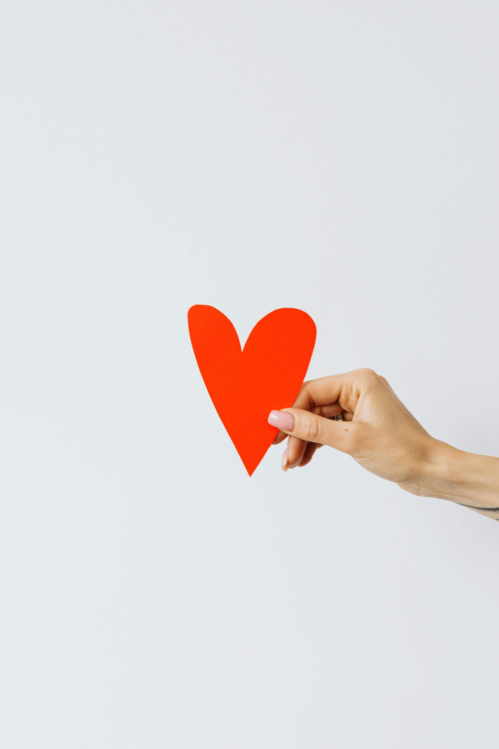 Foto rotes Herz aus Papier, das von einer Hand gehalten wird