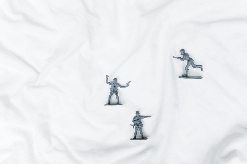 Three grey plastic toy soliders spread out on a crumpled piece of paper. Highlighting the difficulty in tracing your wwi ancestors.