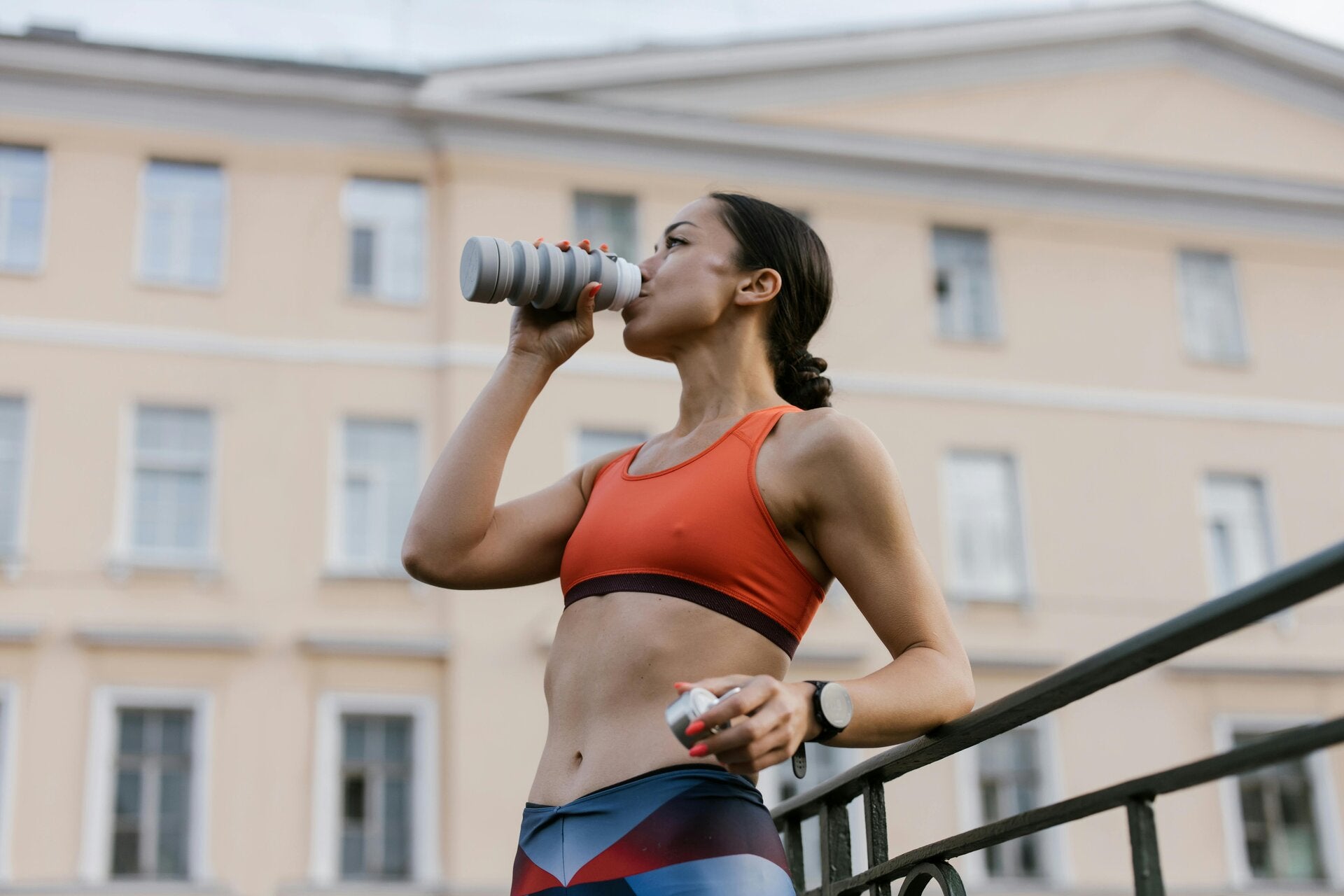 une femme en tenue de sport en train de boire à la gourde
