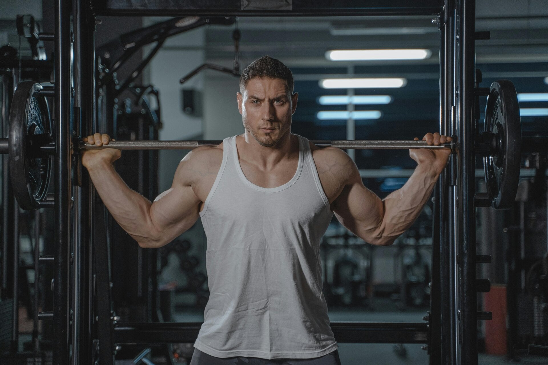 un homme musclé faisant un exercice de musculation debout avec une barre en fer derrière les épaules