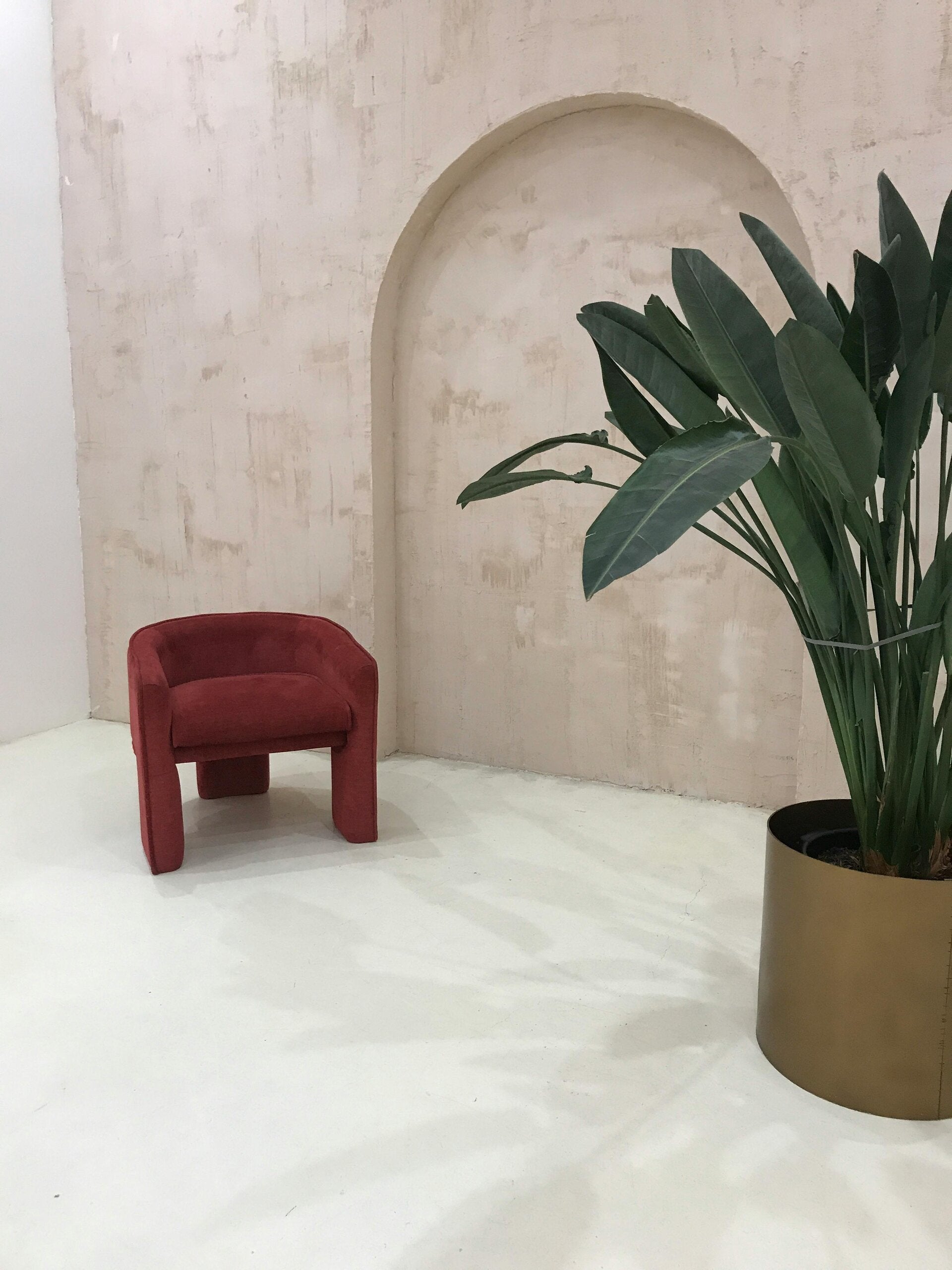 alt="Fauteuil en velours bordeaux – touche élégante dans un salon naturel"
