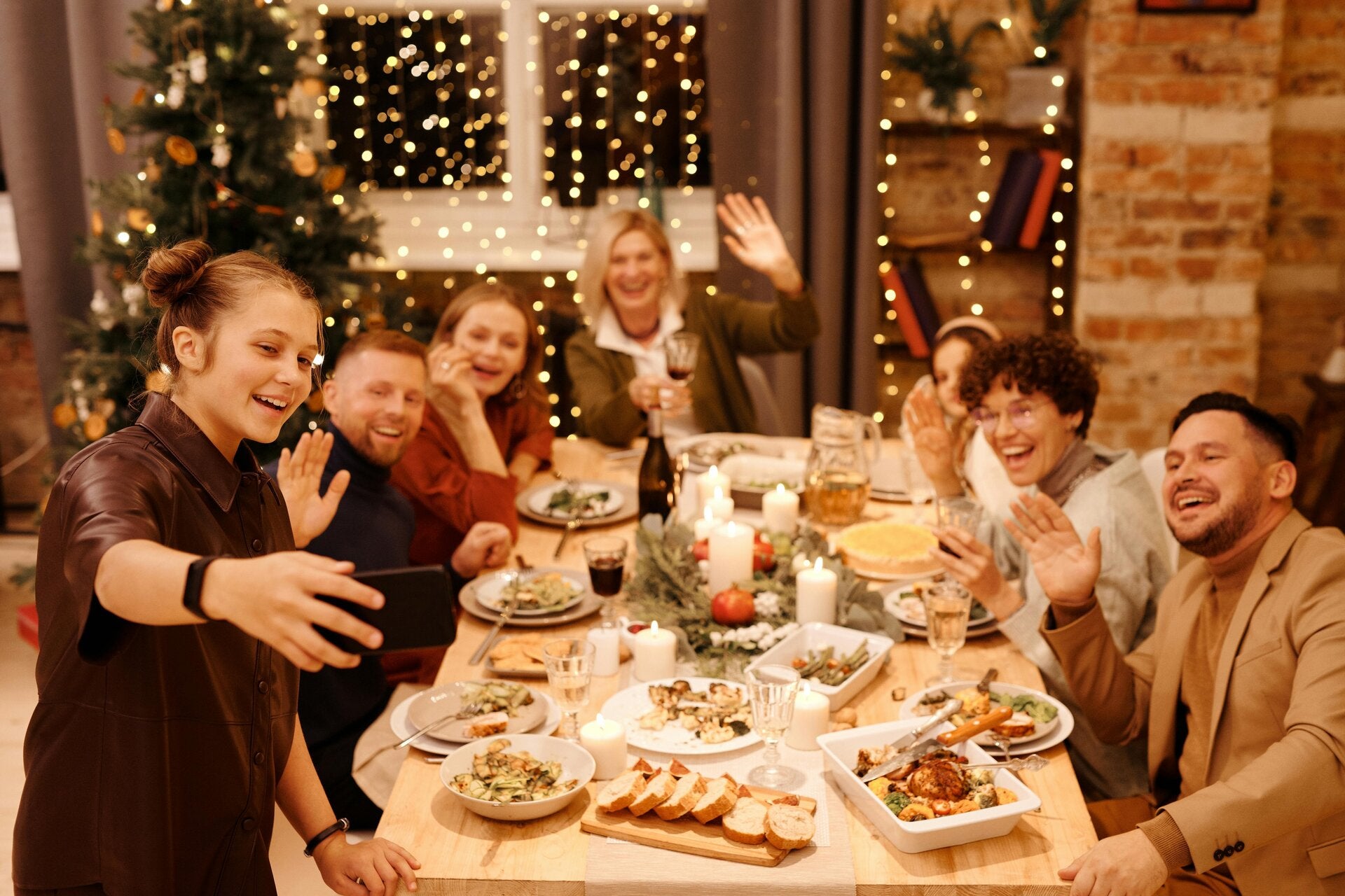 Family smiling gathering around the table full of festive yummy food taking a group selfie. 