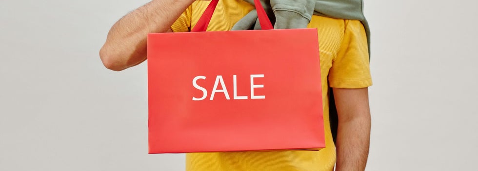 A person holding a shopping bag with the word 'SALE' prominently displayed, signaling a great deal.