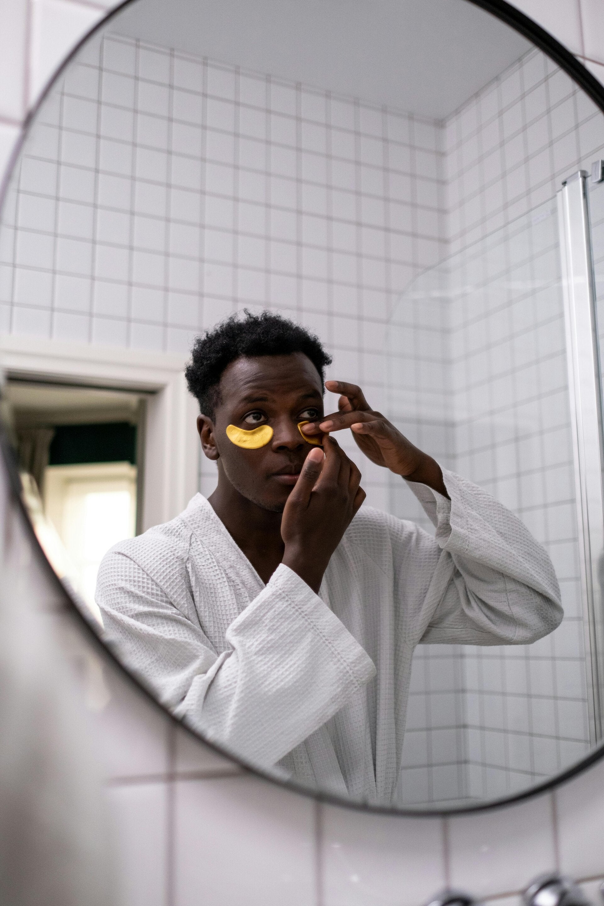 Hombre aplicándose parches de ojos frente al espejo