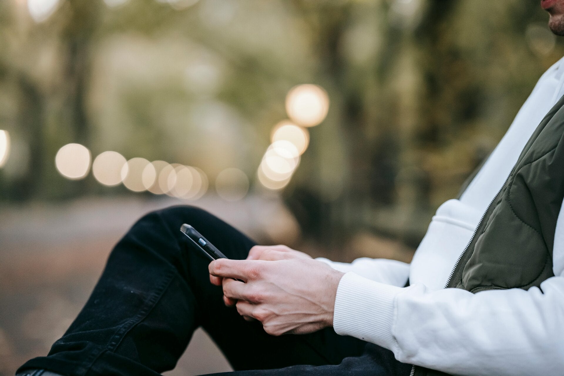 person sitting on a park bench holding a smart phone