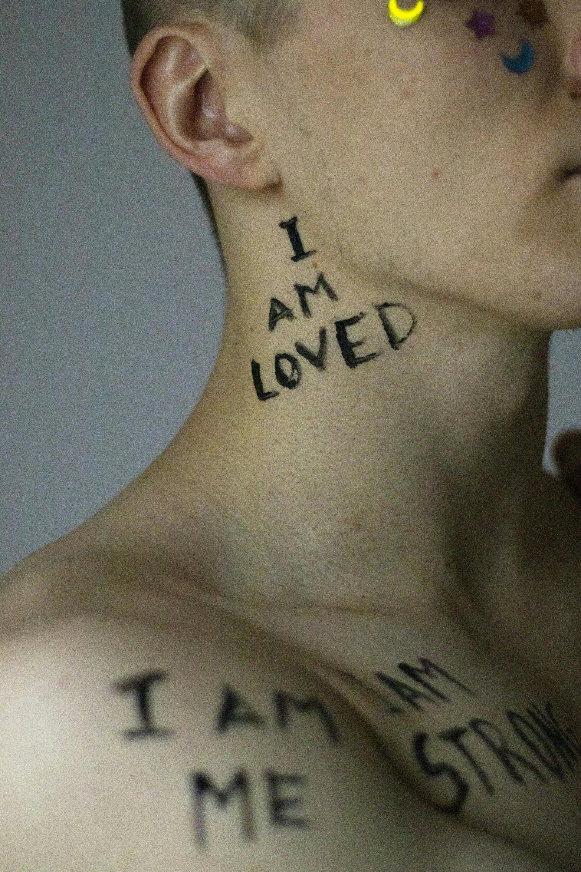 Self portrait or artistic image showing the positive affirmation. I am loved written and boldly on a person skin.