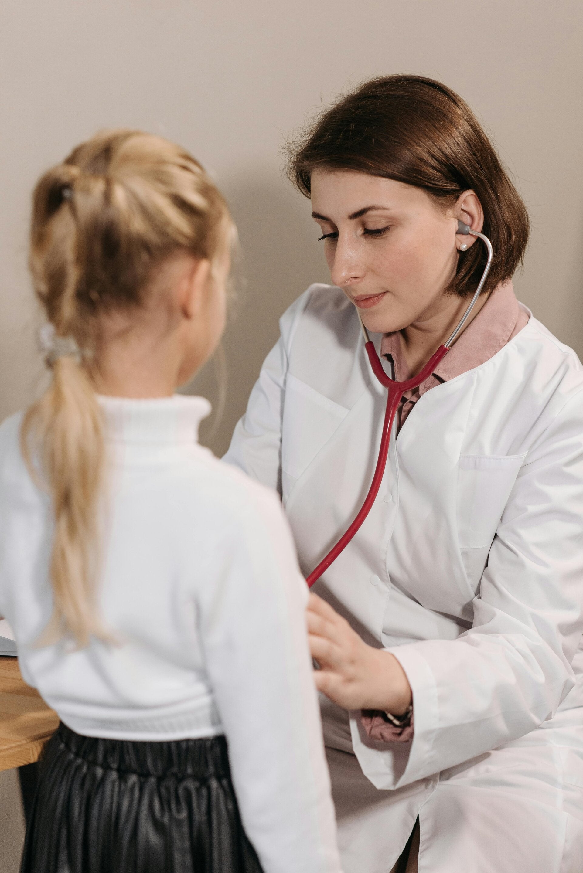 Woman doctor  with a stethoscope examining a girl