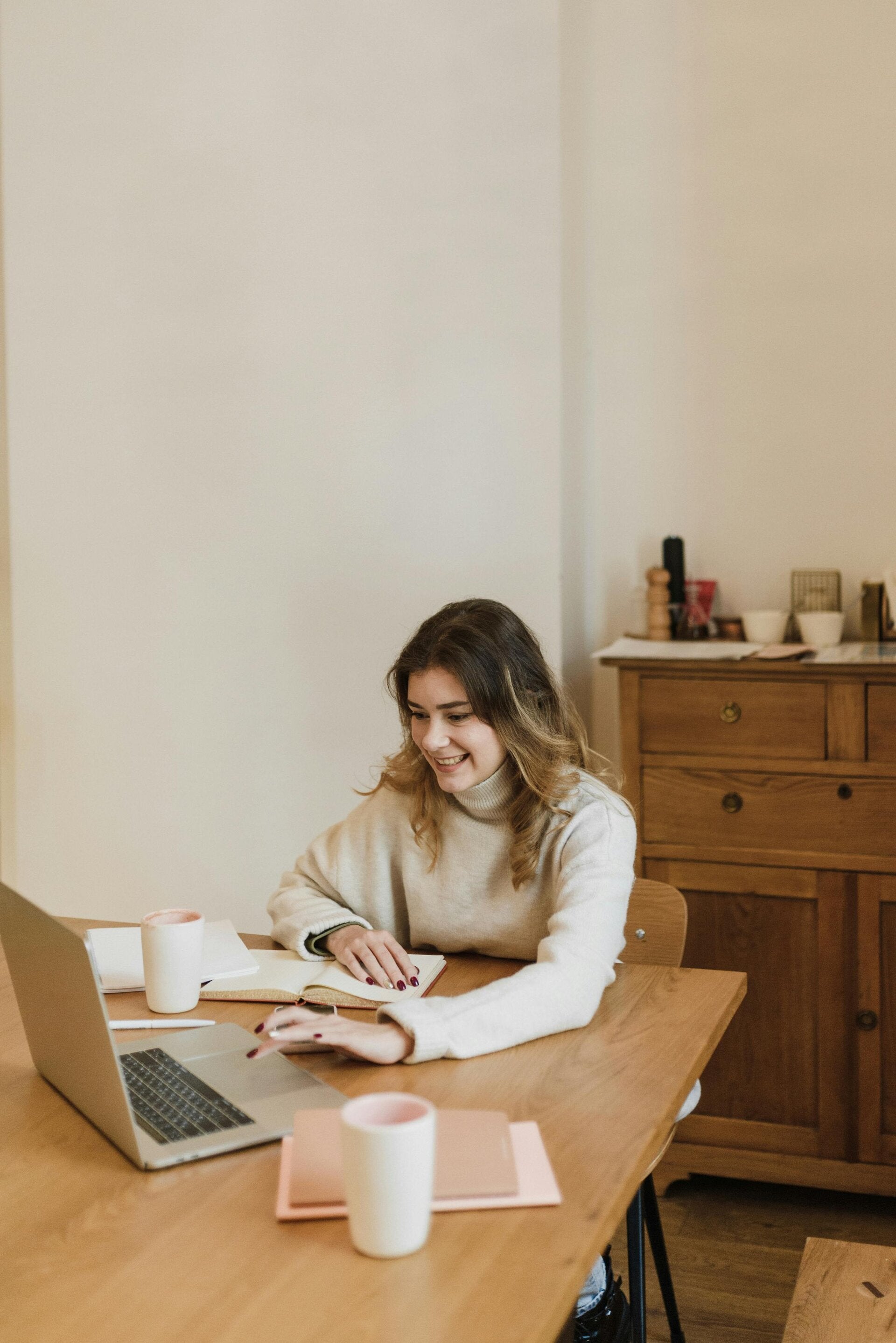 Confident woman working from home at a cozy desk with laptop and coffee