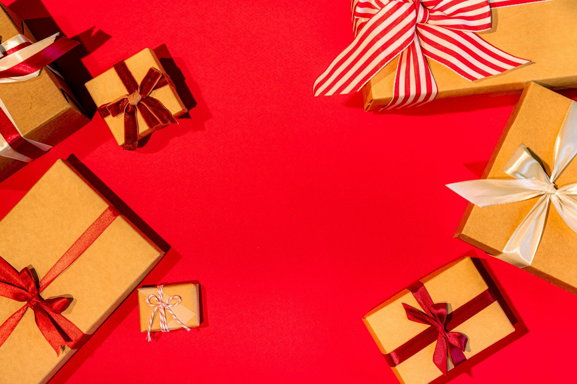 2 bruine cadeautjes met grote rode strik, gefotografeerd op een rode achtergrond