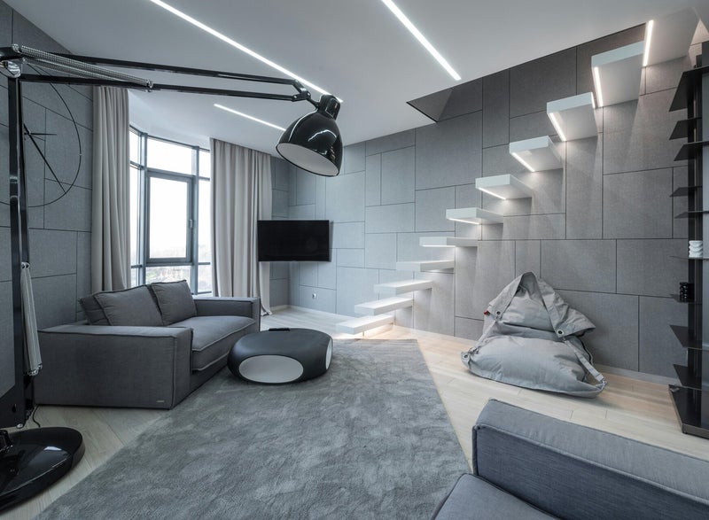 Relax Zimmer - grau - weiße Treppe führt nach oben - im Raum graue Couch grauer Teppich und 2 graue Polstermöbel - große Designerlampe