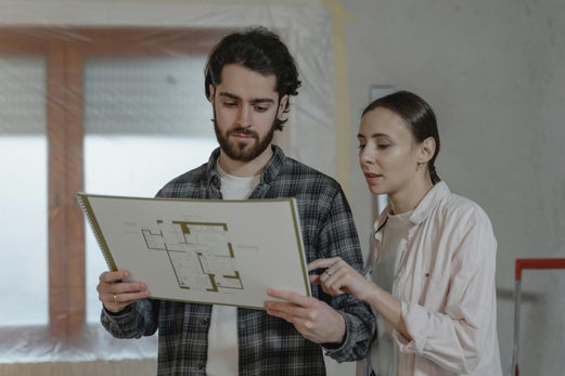 Geometra Edil Valenza mostra il progetto di ristrutturazione a una cliente, illustrando piani e dettagli degli impianti