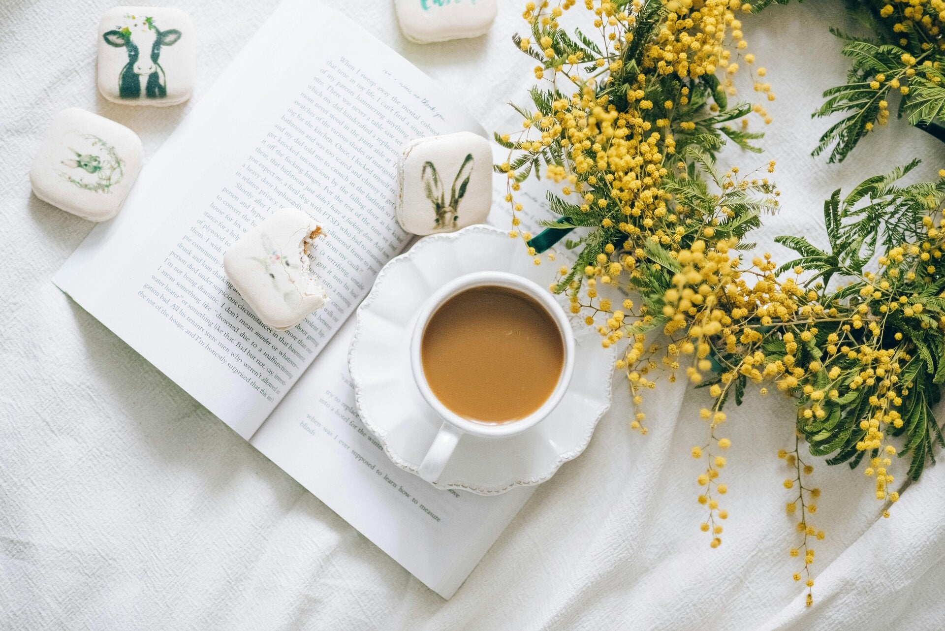 Boek met koffie, koekjes en een bloemenkrans.