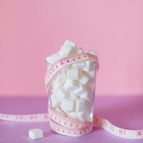 Un verre de sucre avec un mètre ruban qui illustre le rapport avec le poids