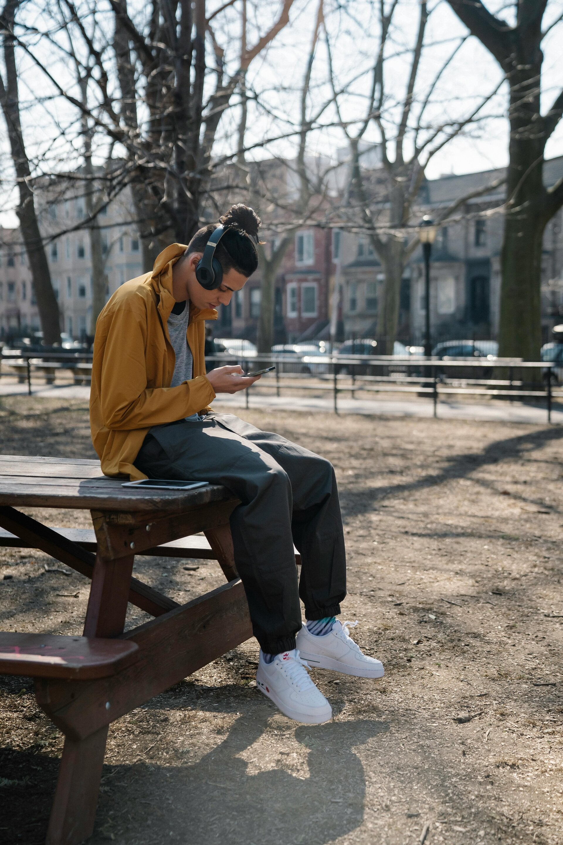 A man on a park bench looking at phone with headphones — example of distracted walking
