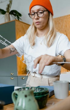 A woman carefully working with wires, showcasing precision and skill in an intricate electrical or crafting project.